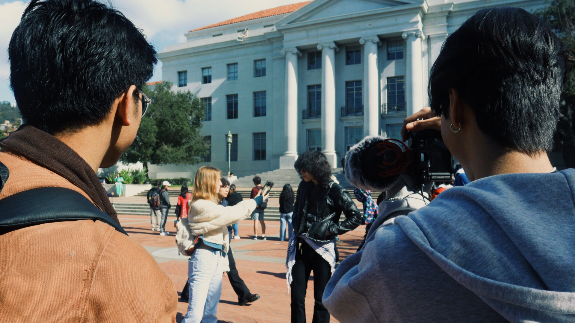 One videographer and one director watch and record as a reporter interviews a student